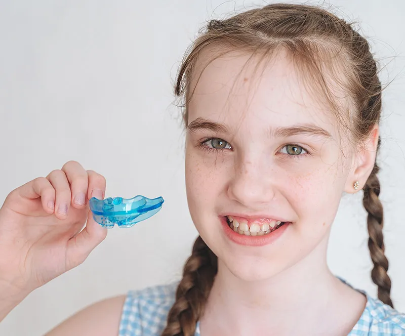 Smiling young patient holding a custom oral appliance