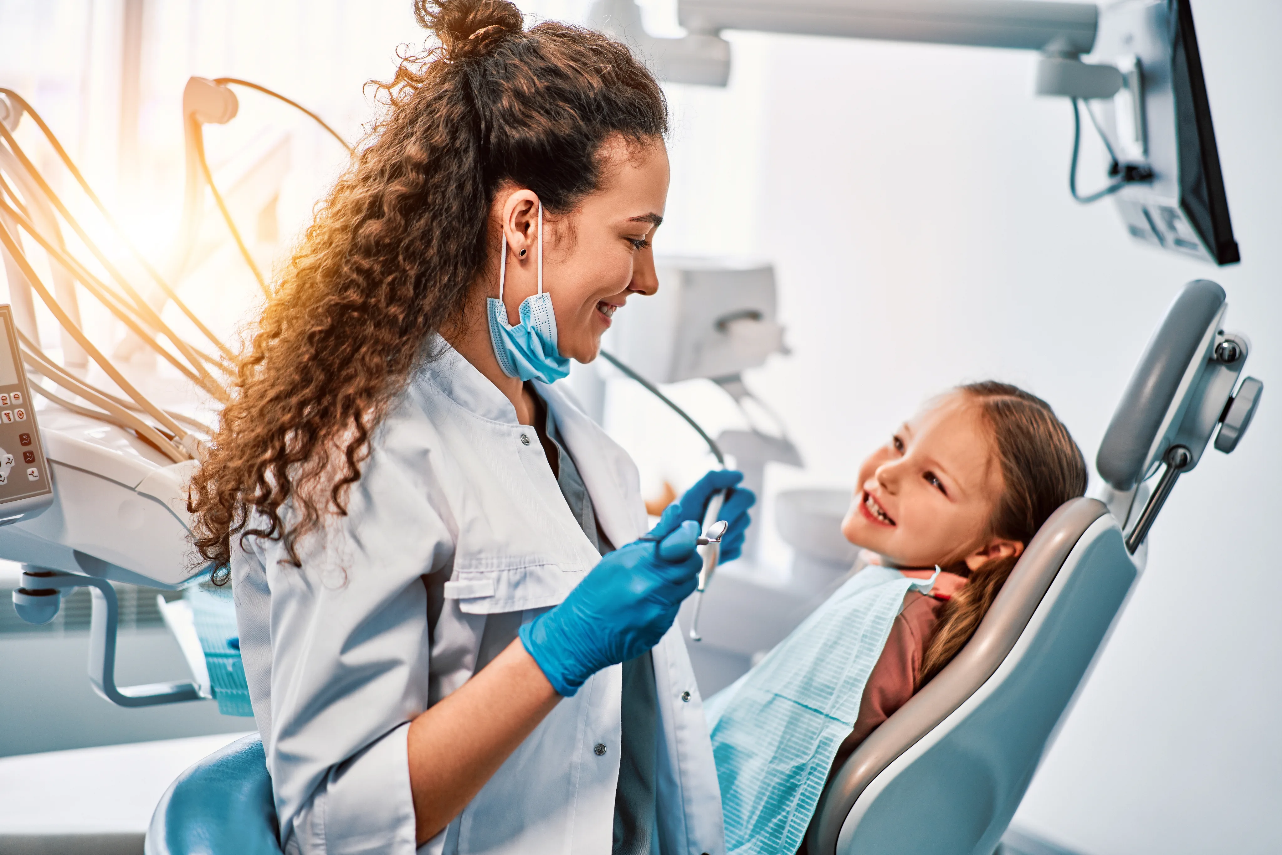 Pediatric dentist placing a sealant on a young patient's molar
